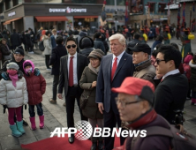 트럼프 상 옆에서 기념촬영하는 사람들